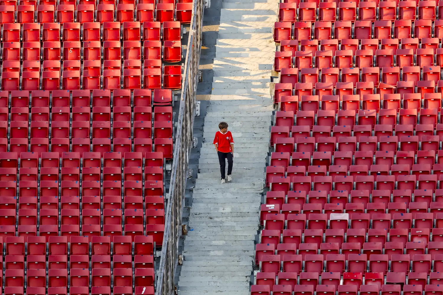 A young fan alone in a stand of empty red seats